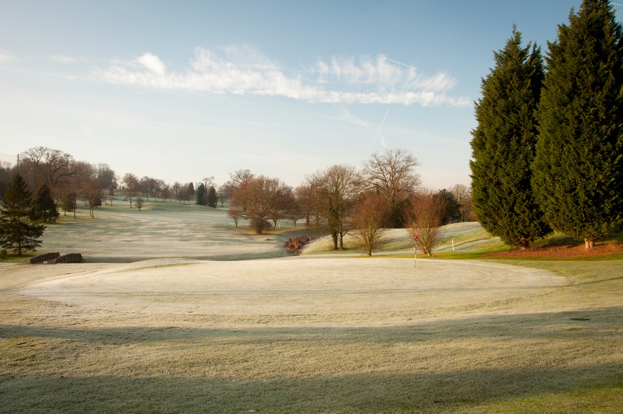 View of a golf course in winter with frost on the grass.