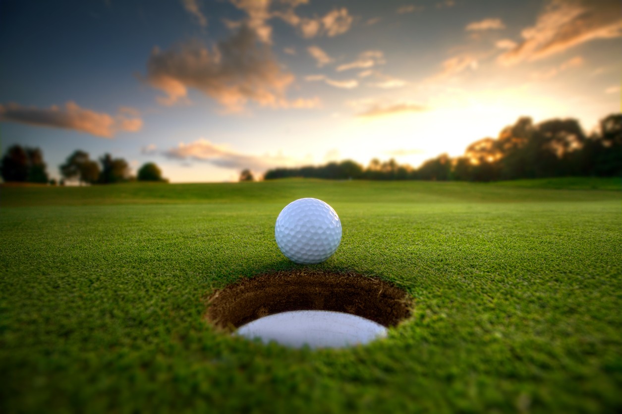 golf-ball-at-edge-of-cup-at-sunset