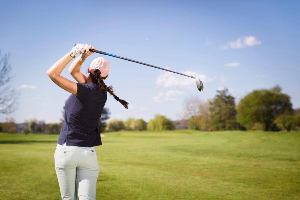 A female golfer swings at a golf ball on a golf course in Central Oregon. 