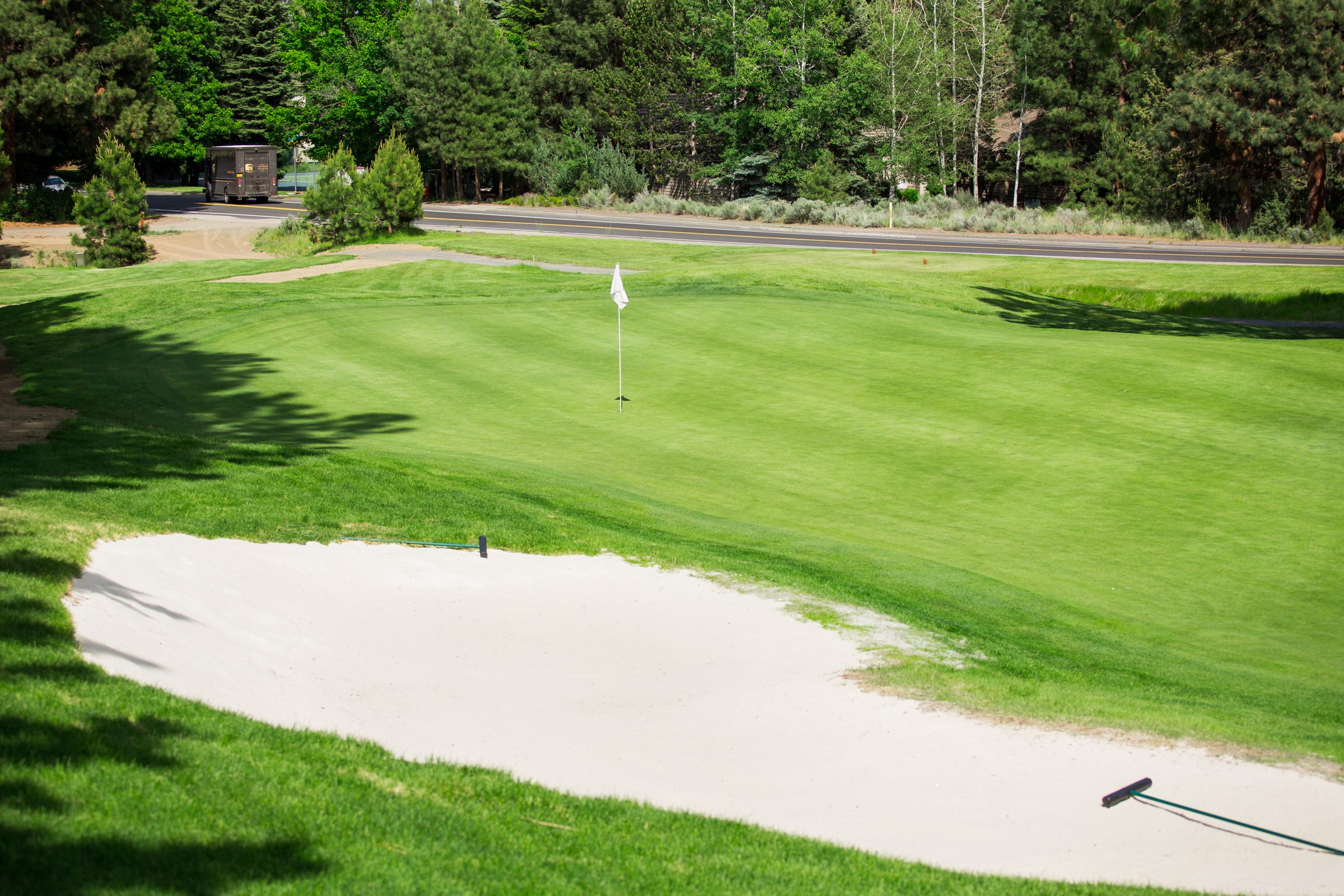 Golf course with sand bunker and flag showing the hole. Scenic green background.