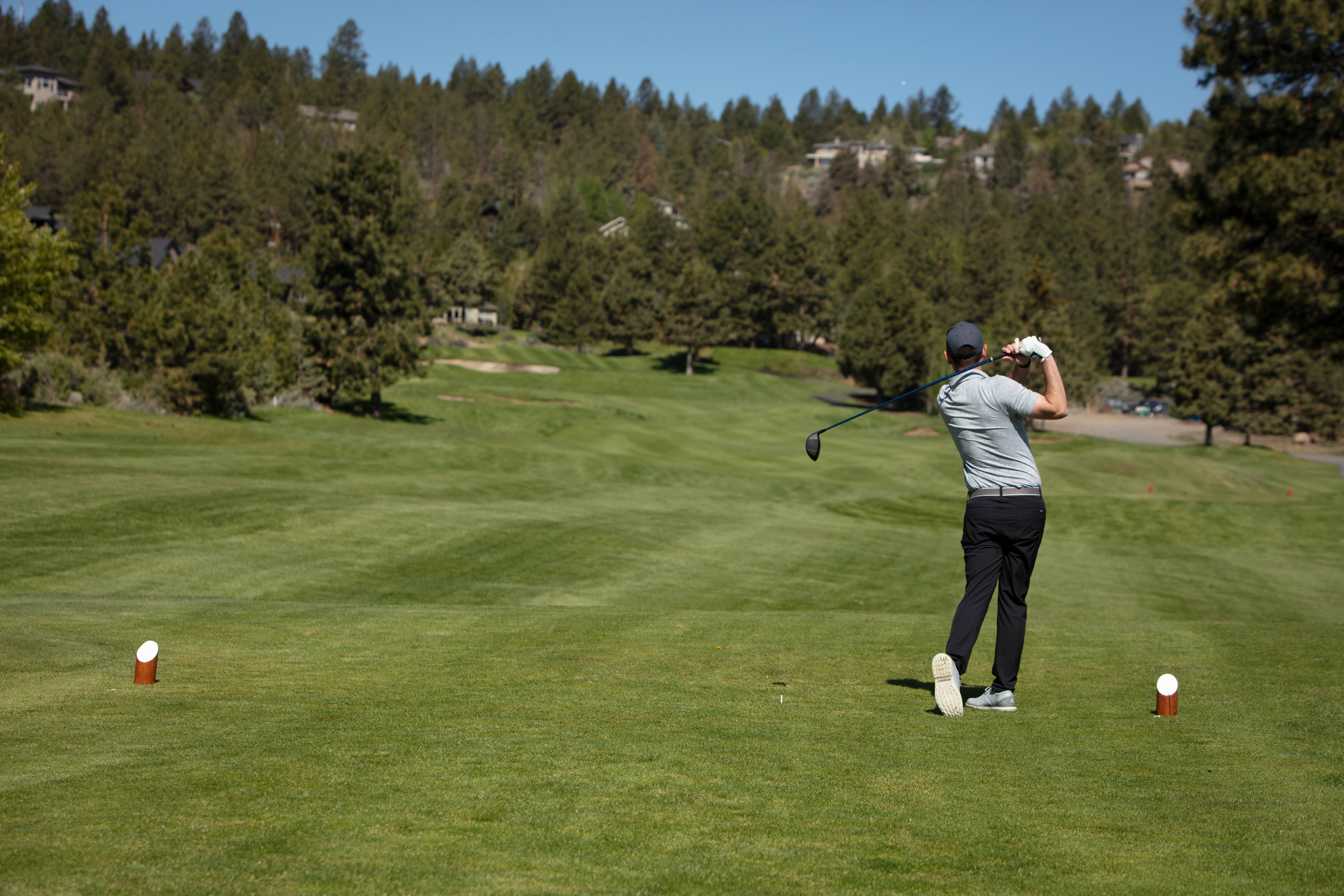 Golfer taking a swing at the ball on RIver's Edge green golf course.