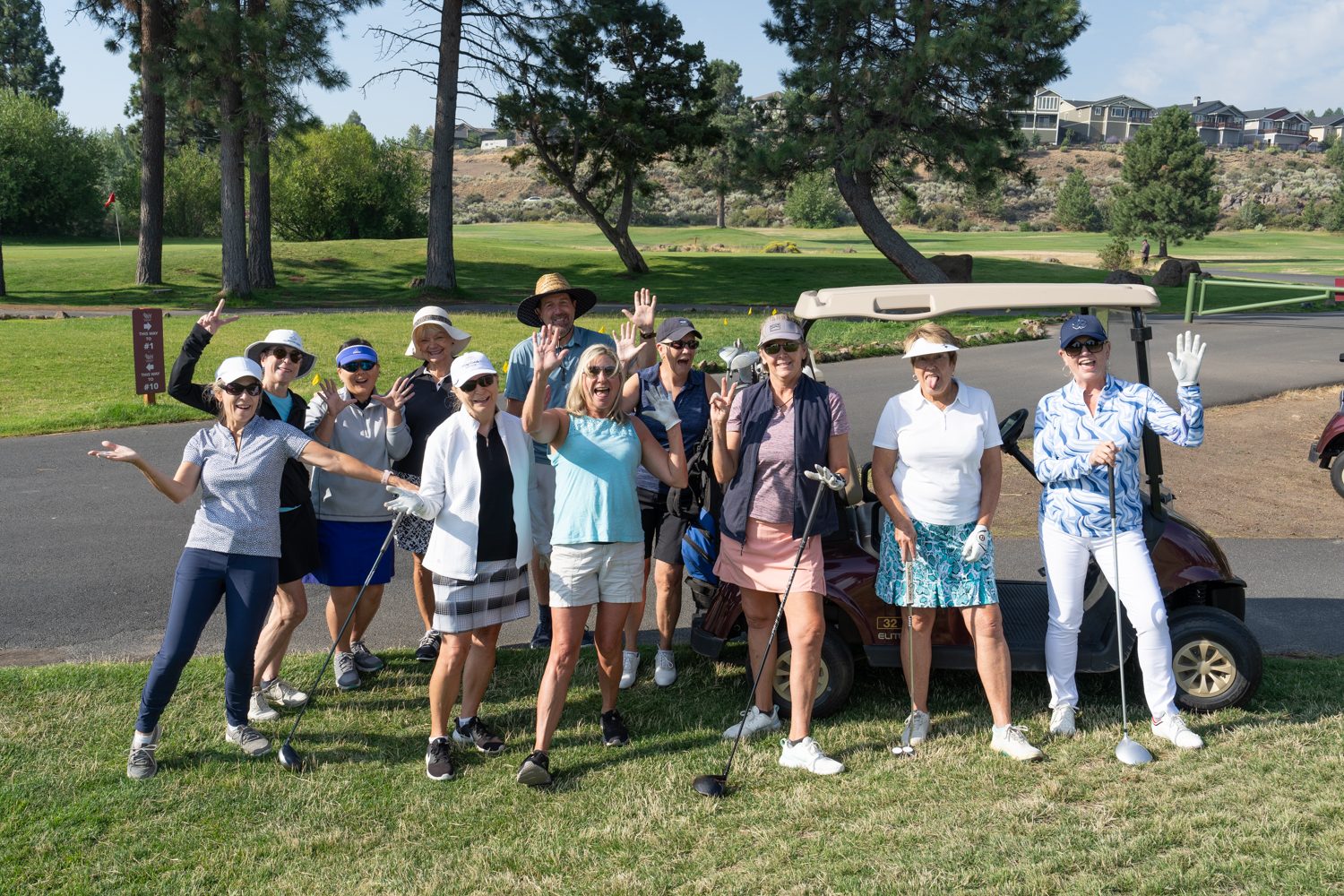 Community of people smiling at the camera in golf attire at River's Edge golf course.