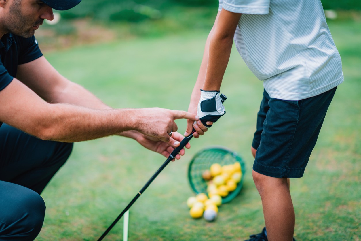 Golf pro teaching showing a child the proper grip on a golf club. 